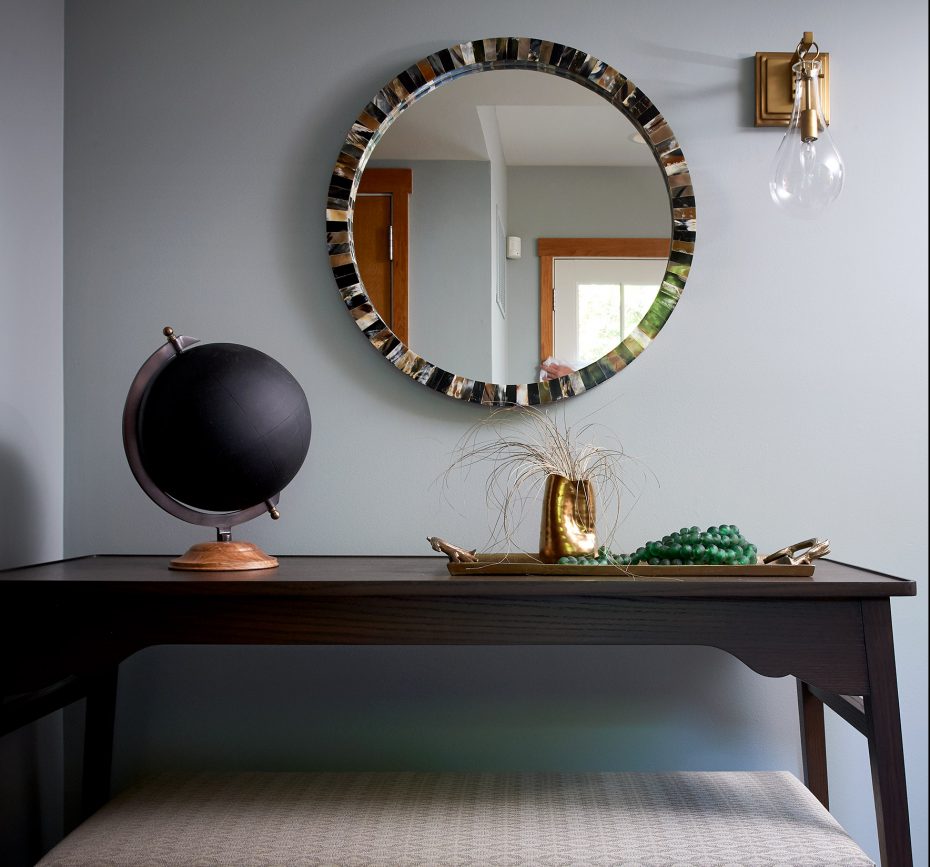 entry table in dark wood with black chalk globe and round shell mirror with brass sconce