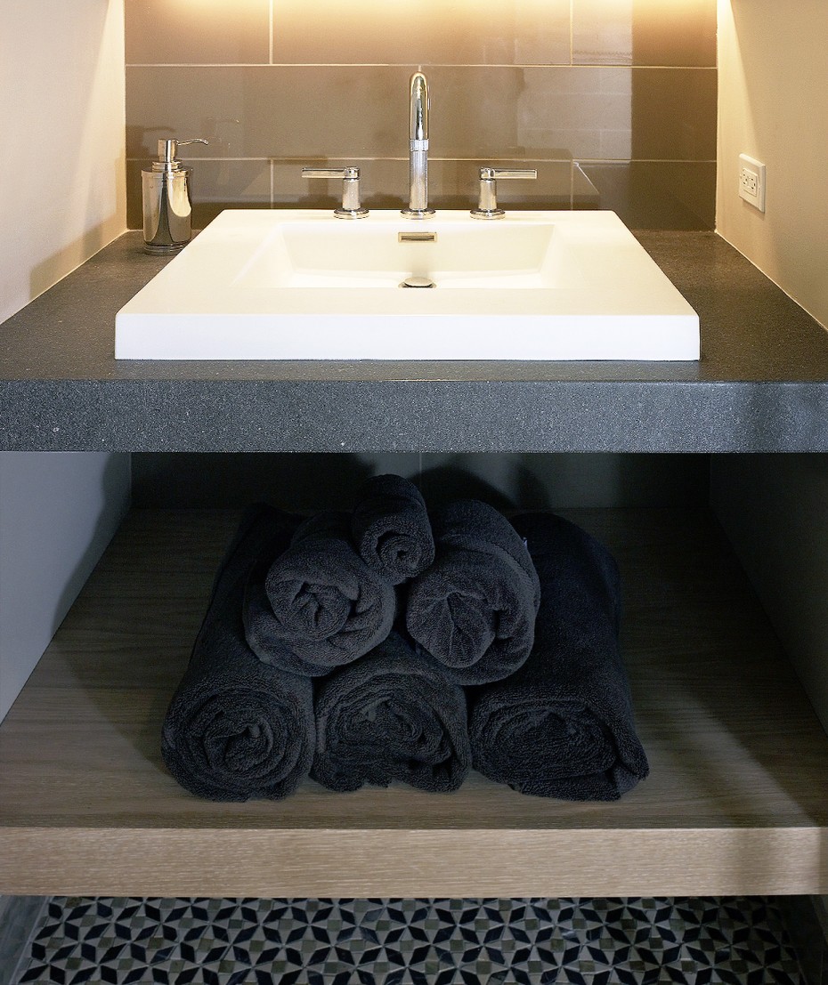 detail of square sink, grey stone top, open shelving. Kallista faucets