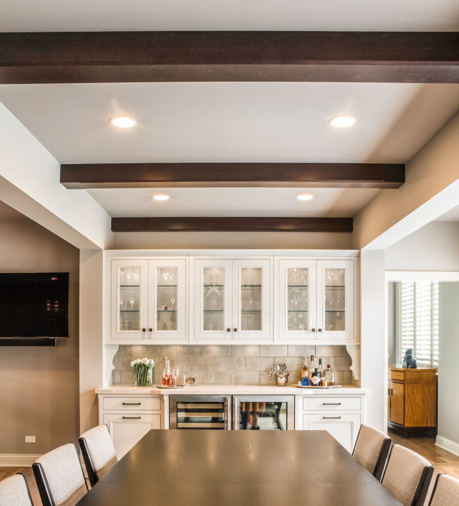 transitional style dining room with bar, white cabinets and beamed ceiling. Modern kitchen design with dark walnut wood and painted cabinets. Subzero refrigerator. Ann Sacks Tile. White kitchen. Kitchen Renovation. Modern interior.