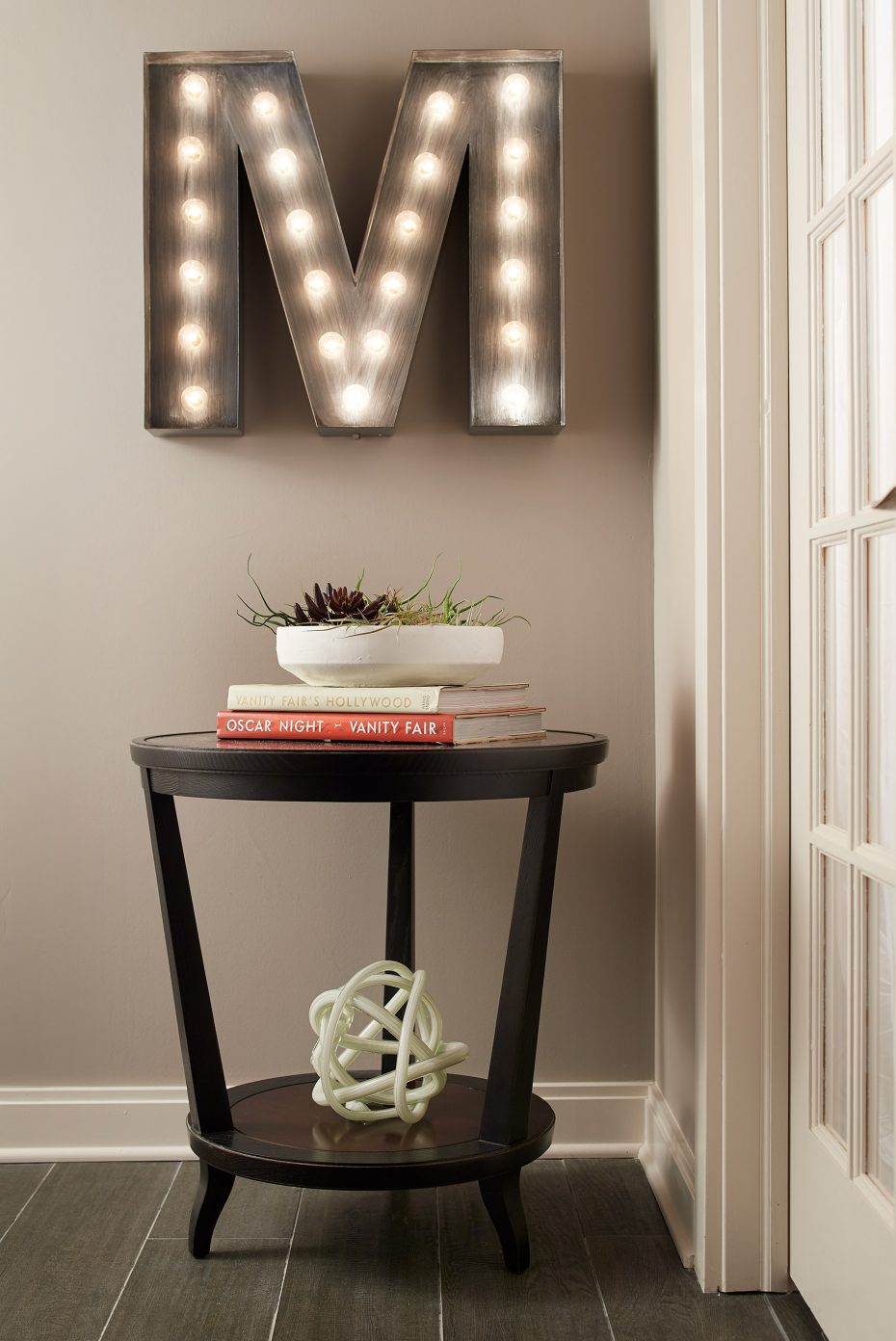Large letter M in lights above a Hickory Chair wood table