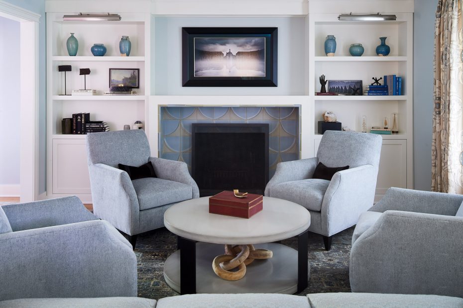 living room with blue chairs, fireplace with white bookshelves and ann sacks tile around the fireplace