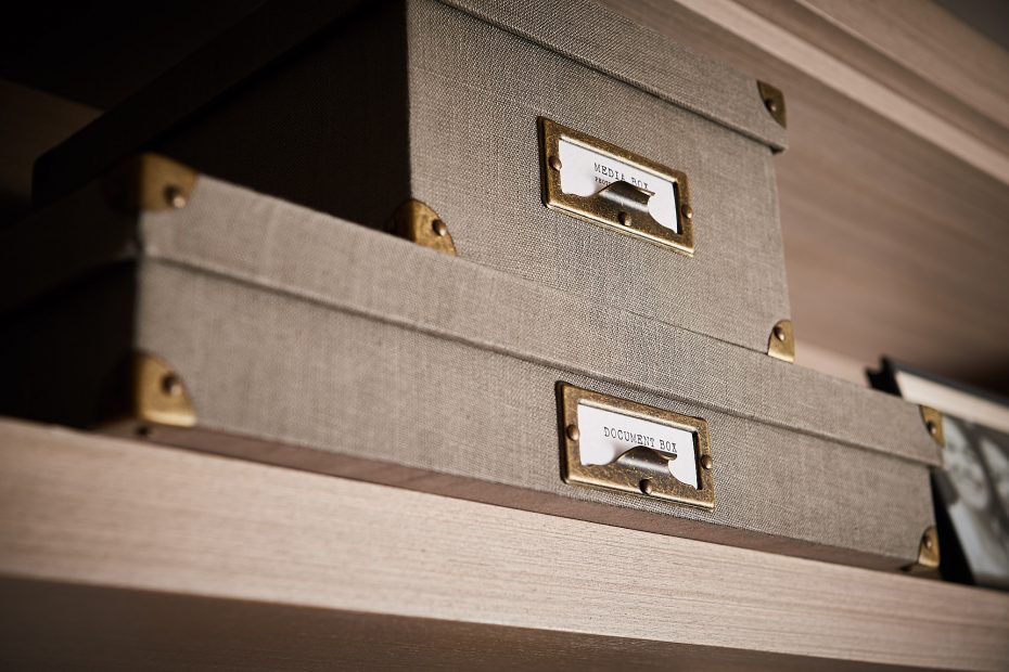 stacked beige linen boxes with metal tab labels