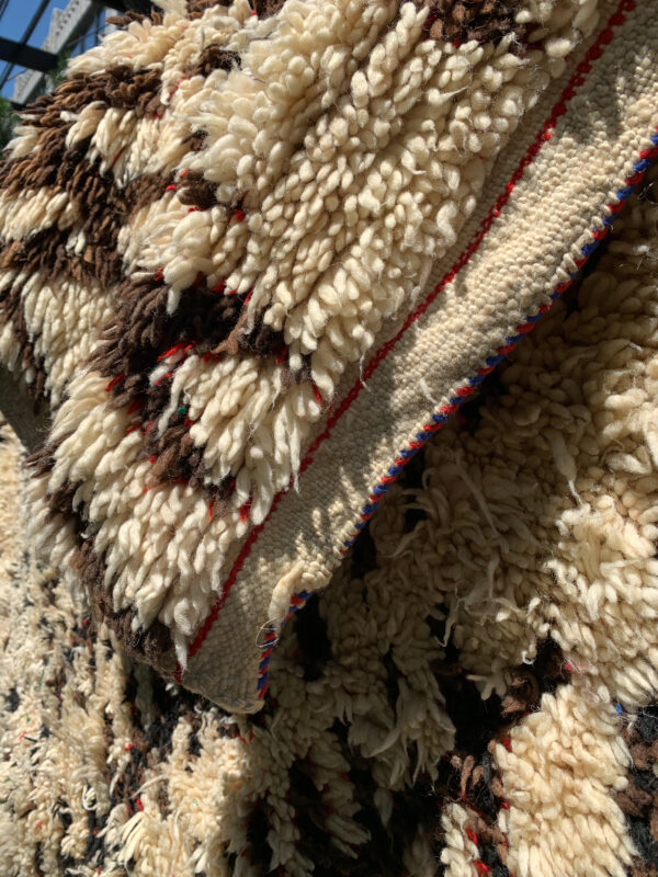 close up of red and blue edge detail. 10-6” x 6 Saw Moroccan rug, cream and brown with flecks of red and green. SKU 142-12 $1900