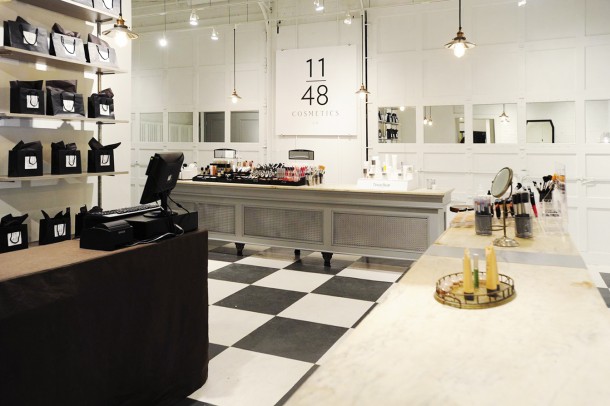 cosmetics store with black and white checked floor, vintage grey transaction counters with white marble tops, white garage doors with mirrored insets