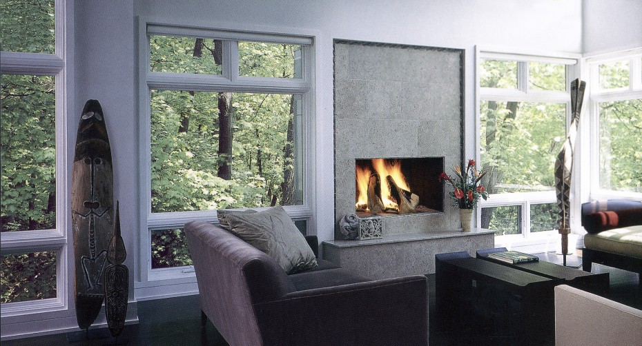 fireplace surrounded by floor to ceiling windows with large wooden piece of art
