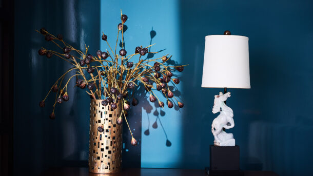Chicago Interior Design. Blue lacquered walls with vintage carved stone lamp of a horse and perforated brass vase with purple flowers