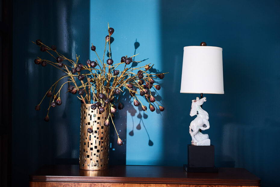 Chicago Interior Design. Blue lacquered walls with vintage carved stone lamp of a horse and perforated brass vase with purple flowers